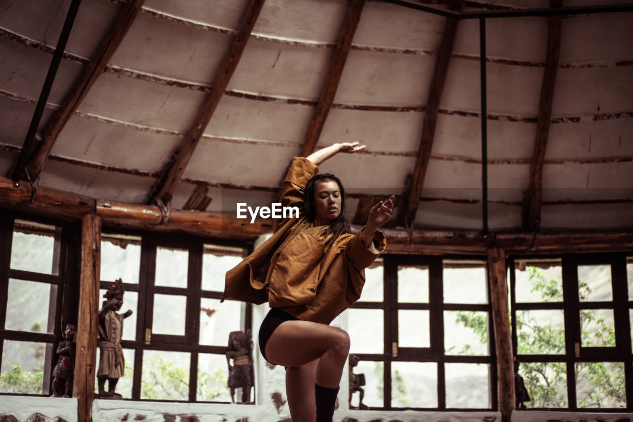 Mixed race fashionable dancer dances in stone and straw dome studio