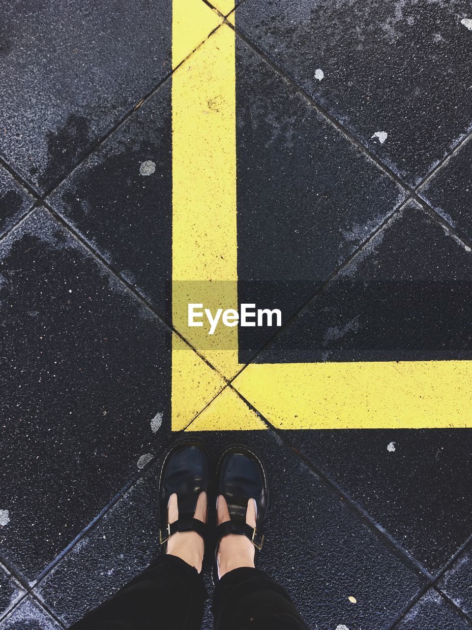 Low section of woman standing by yellow line on pavement
