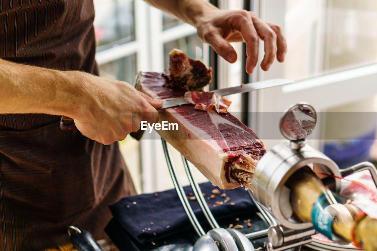 Midsection of man cutting meat