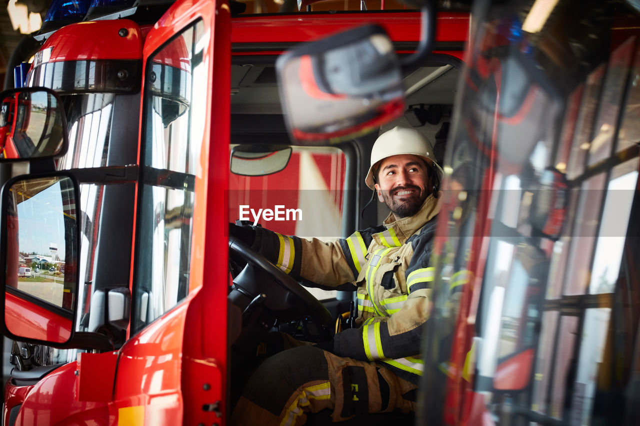 Firefighter looking away while sitting in fire truck at fire station