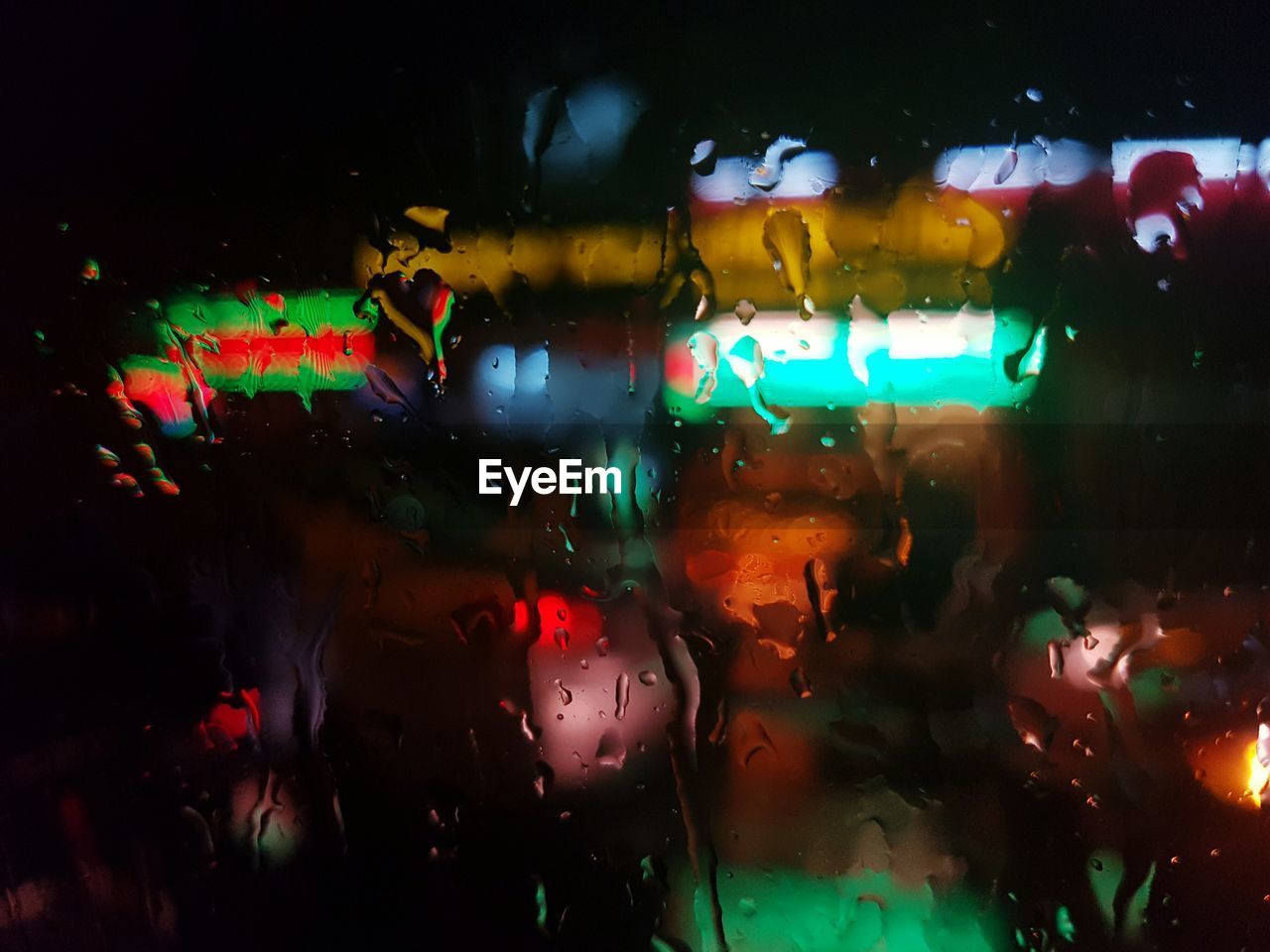 Close-up of wet window in rainy season with night city lights