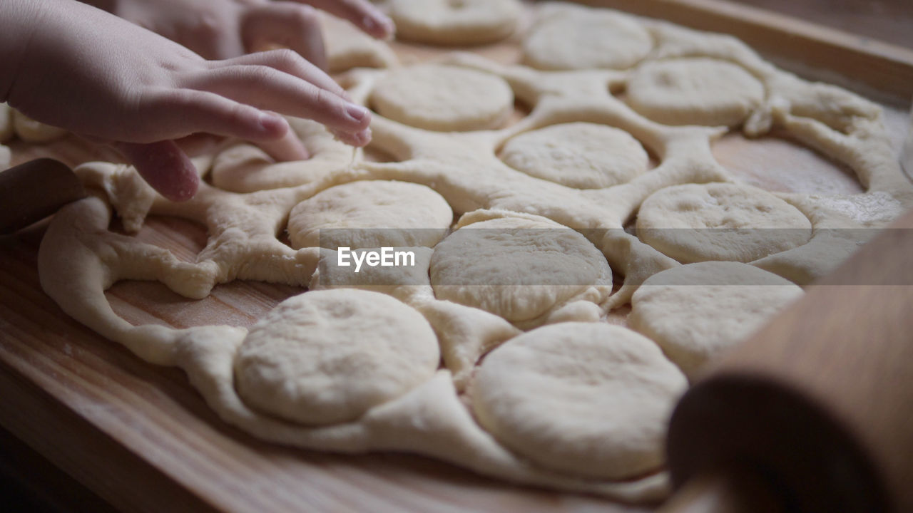 Cropped hands of kid on dough