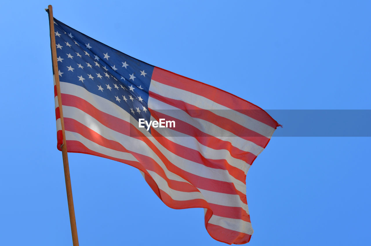 LOW ANGLE VIEW OF AMERICAN FLAG AGAINST CLEAR SKY