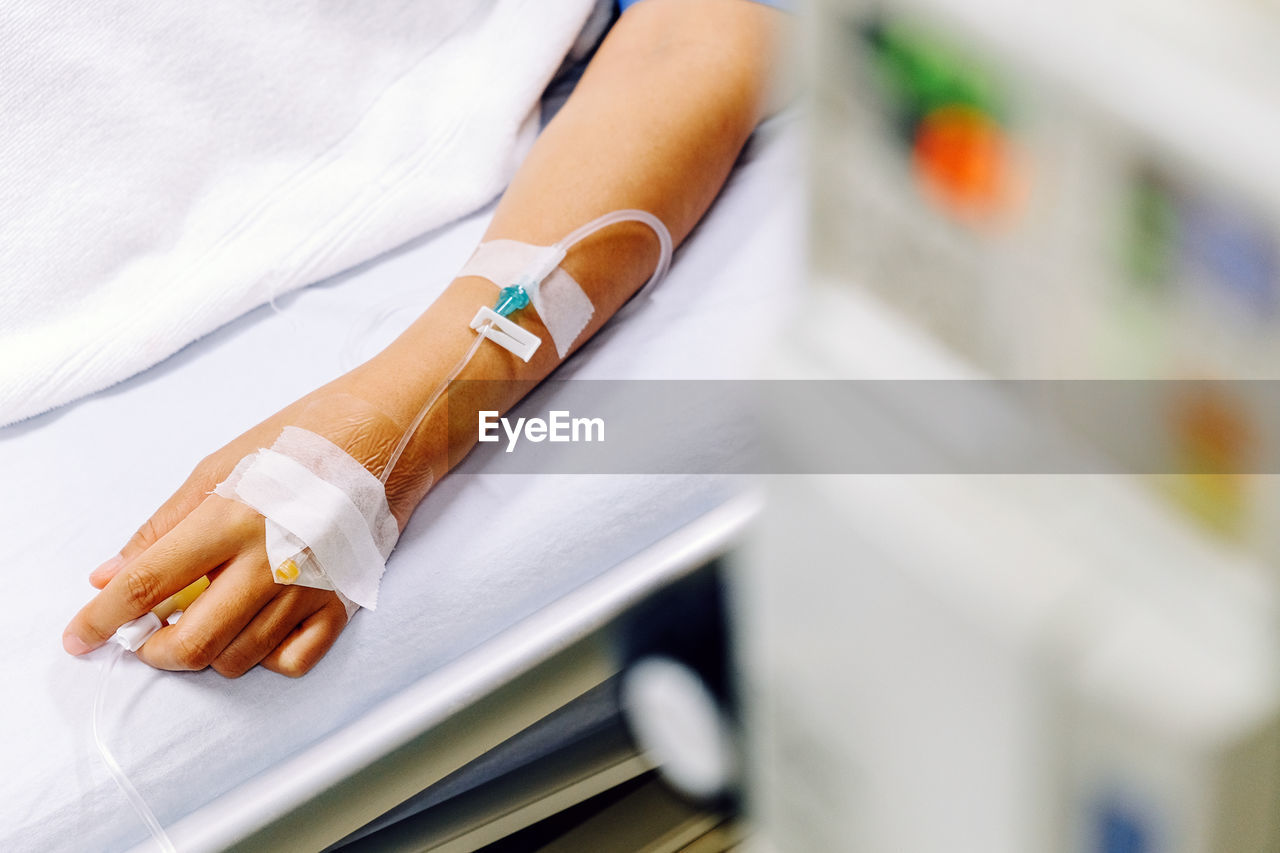 Cropped hand of female patient with iv drip on hand at hospital