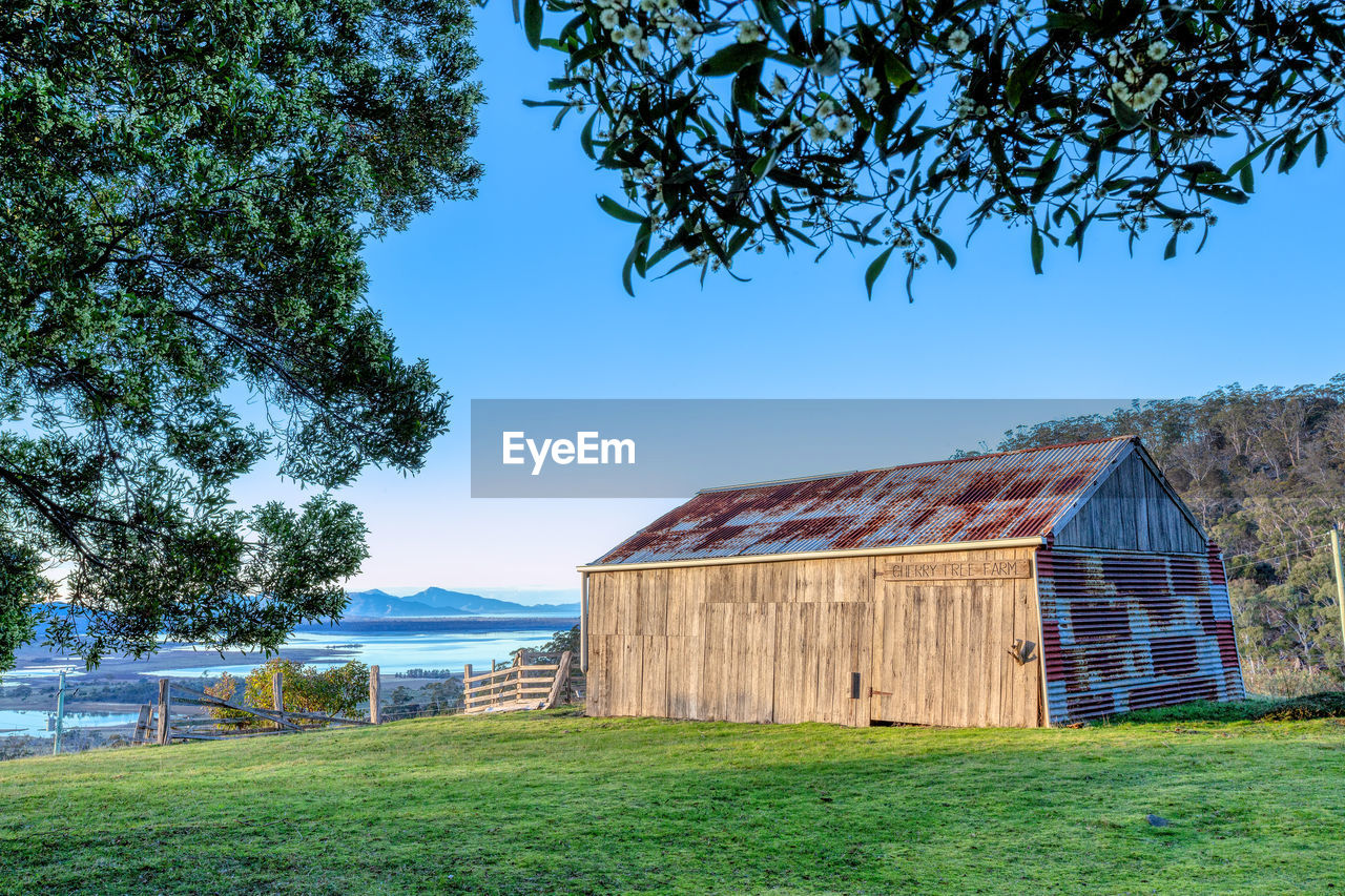 BARN ON FIELD AGAINST SKY