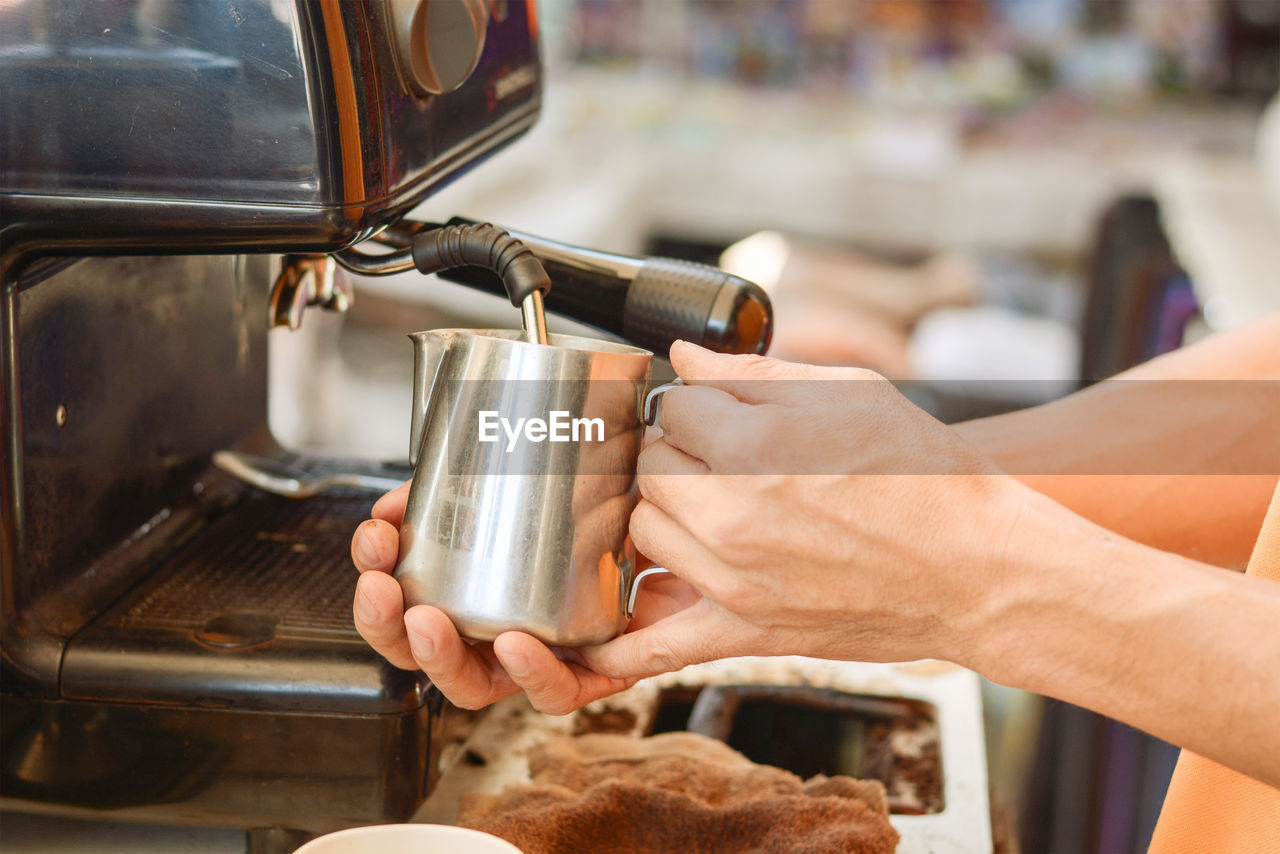 Cropped hands making coffee in cafe