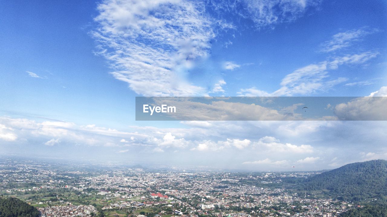sky, cloud, city, architecture, horizon, cityscape, built structure, building exterior, nature, building, landscape, environment, mountain, blue, mountain range, scenics - nature, residential district, aerial view, outdoors, high angle view, no people, travel destinations, day, beauty in nature, travel, urban skyline, town, sunlight, tree, horizon over land, tourism, cloudscape, city life
