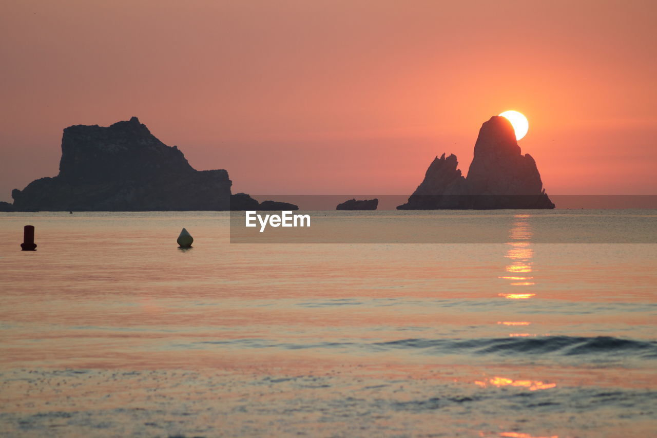 Scenic view of rocks in sea against sky during sunset