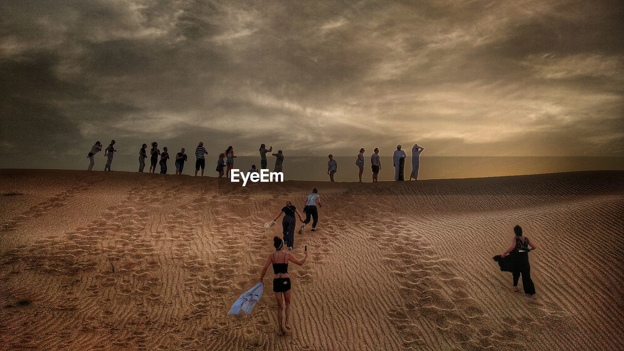 PEOPLE ON BEACH AGAINST SKY