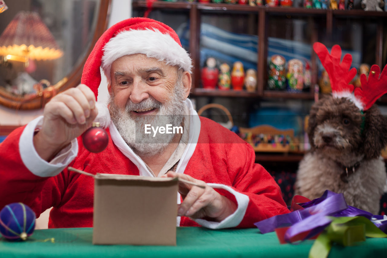 Senior man in santa claus costume sitting at home