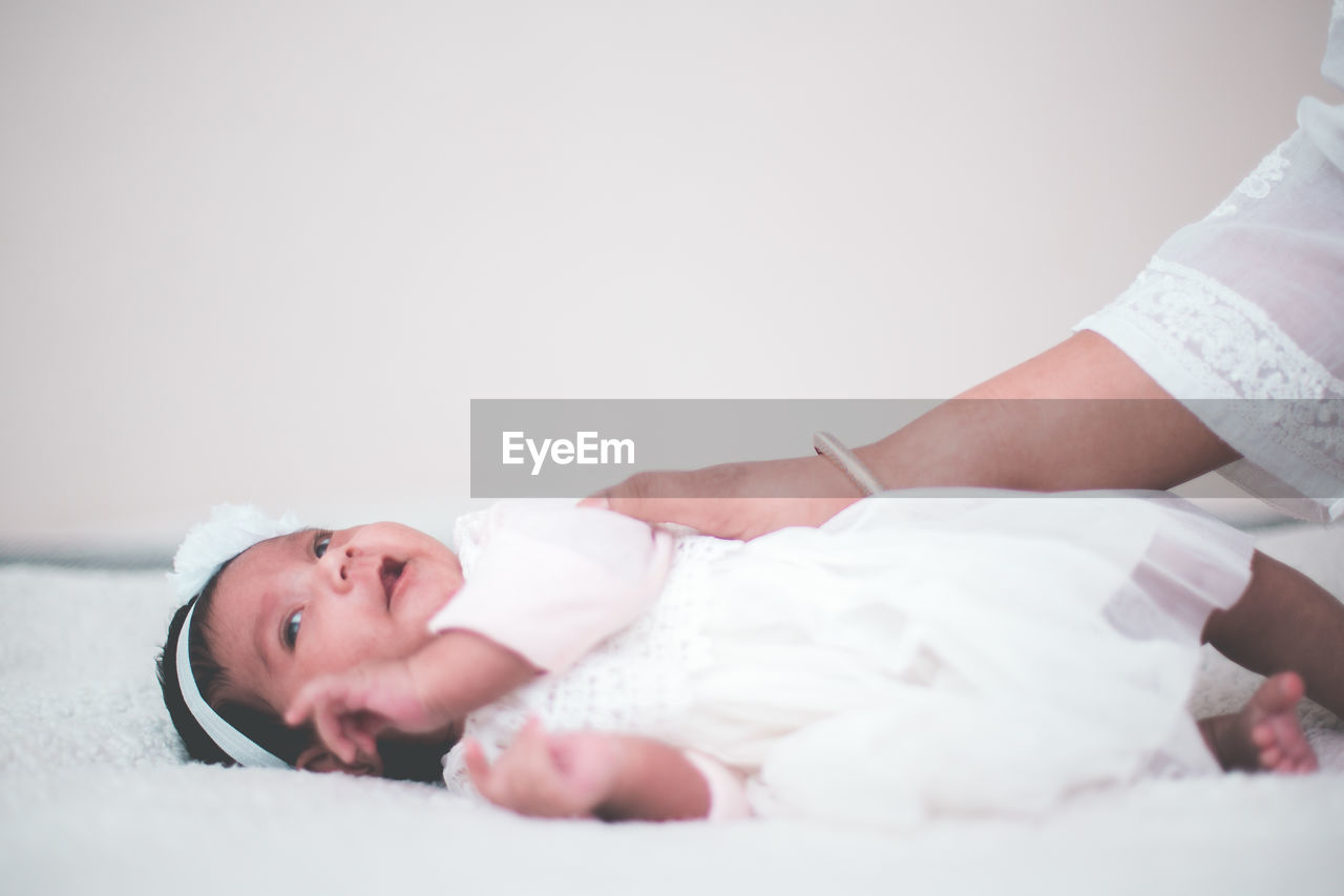 Close-up of mother adjusting daughter on bed