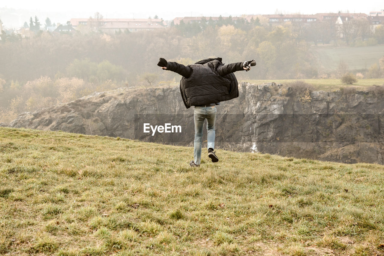 Rear view of man jumping on field