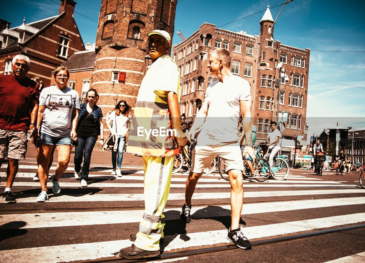 PEOPLE WALKING ON ROAD AGAINST BUILDINGS