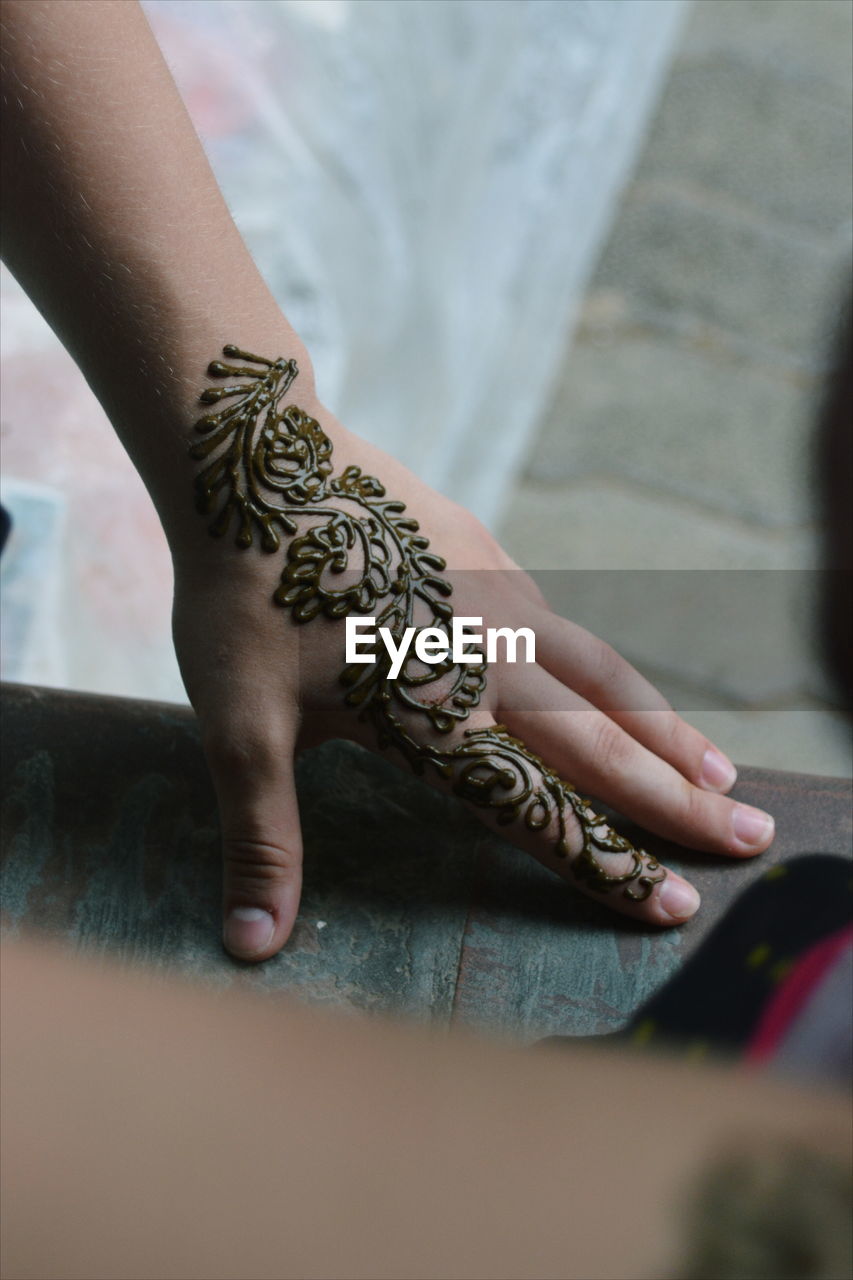 Close-up of woman with henna tattoo on hands