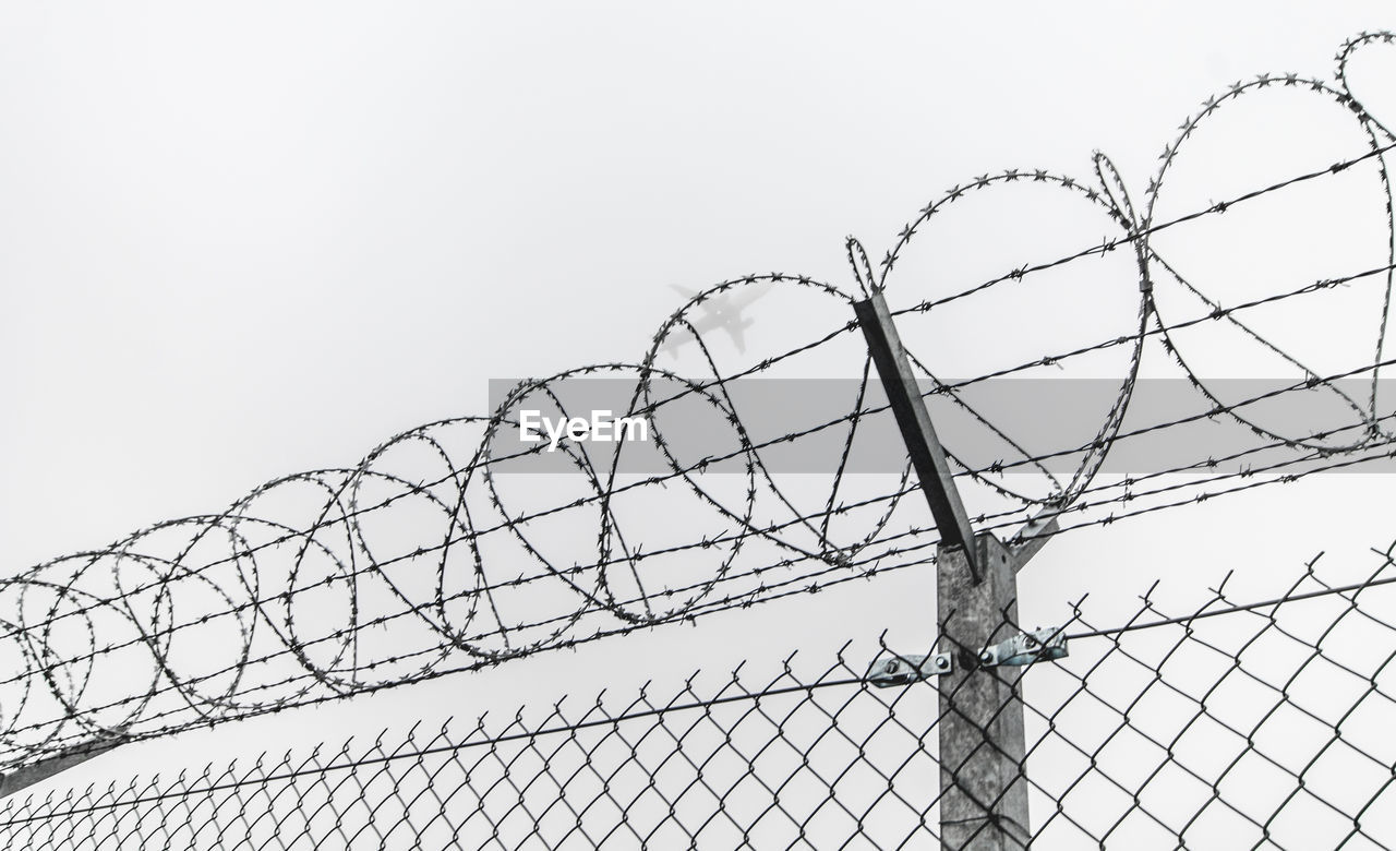 Low angle view of barbed wire fence against clear sky