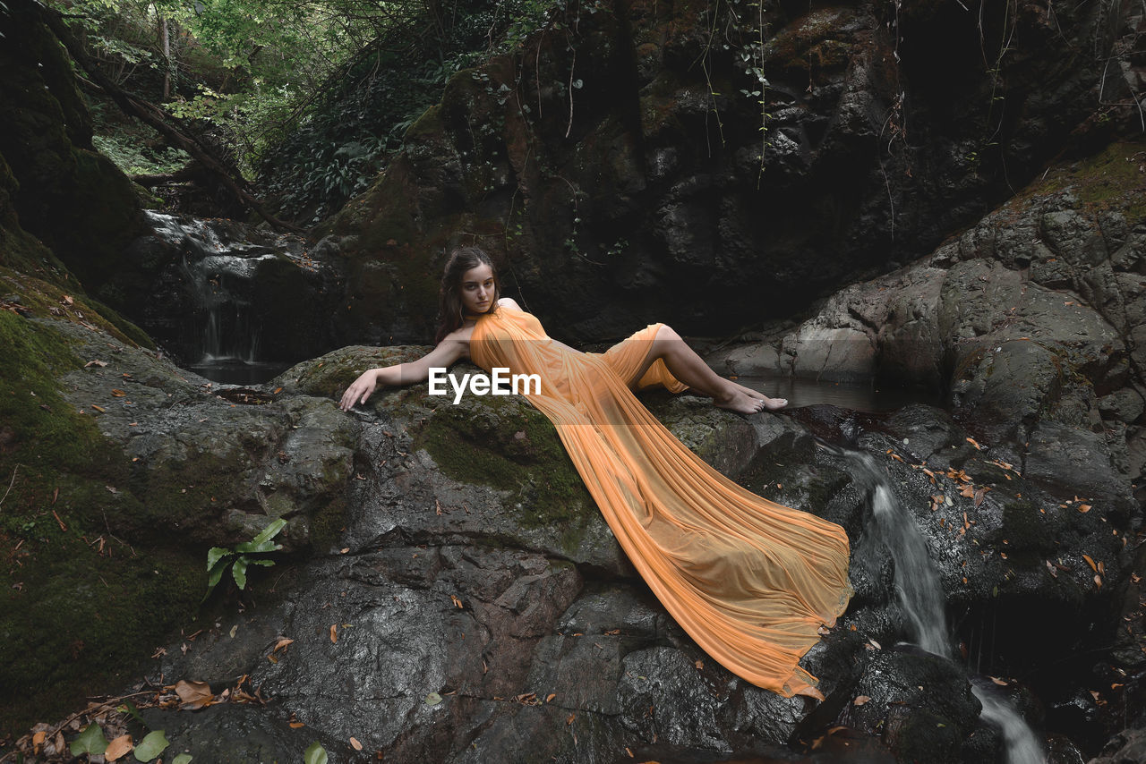 Woman in orange dress lying on rocks