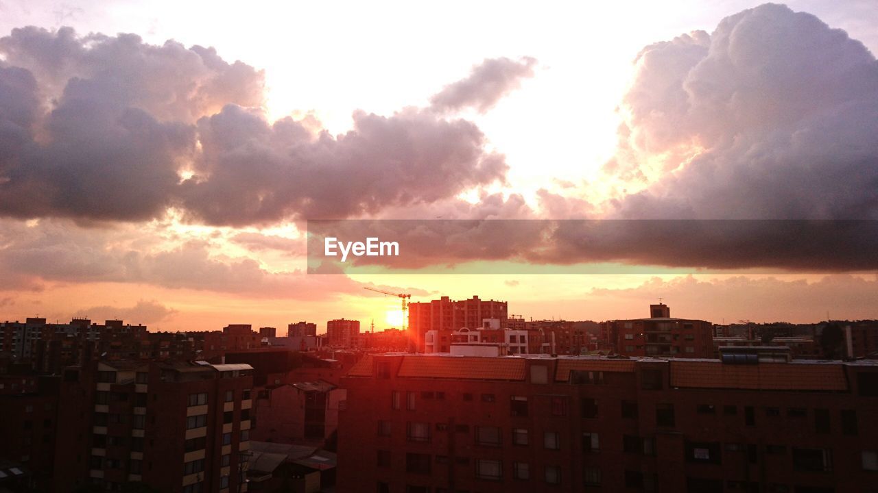 Buildings in city against cloudy sky during sunset