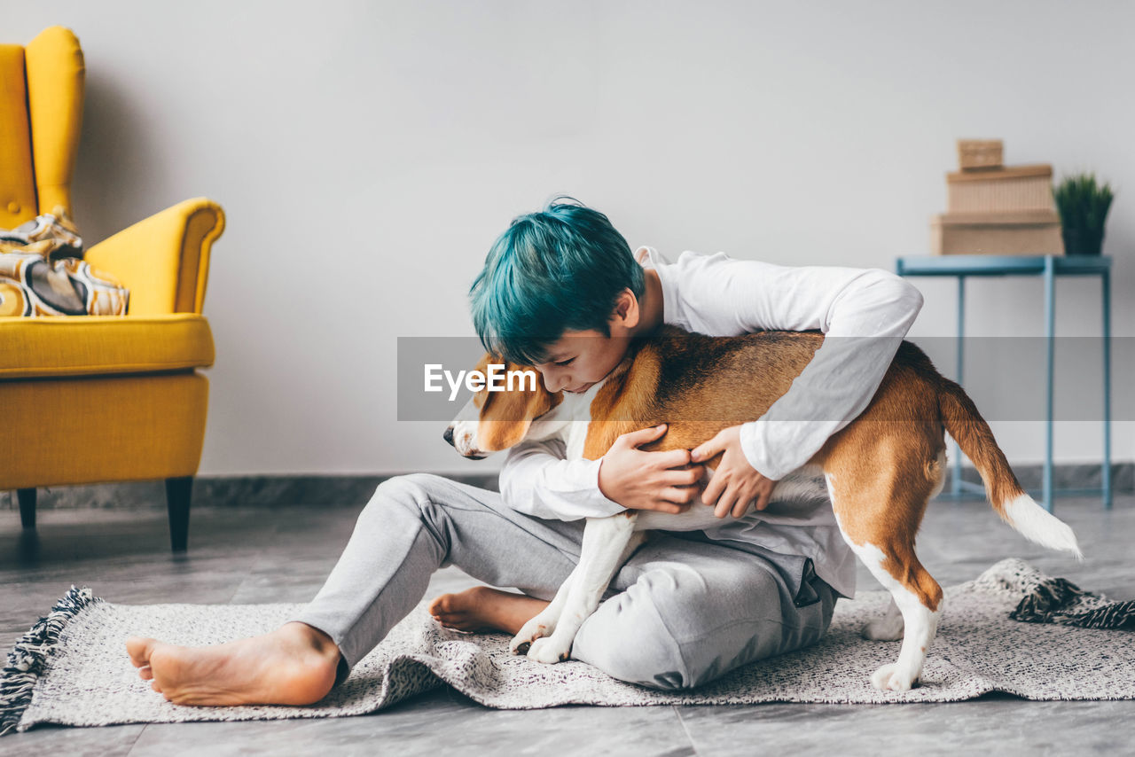 side view of young woman with dog sitting on sofa at home