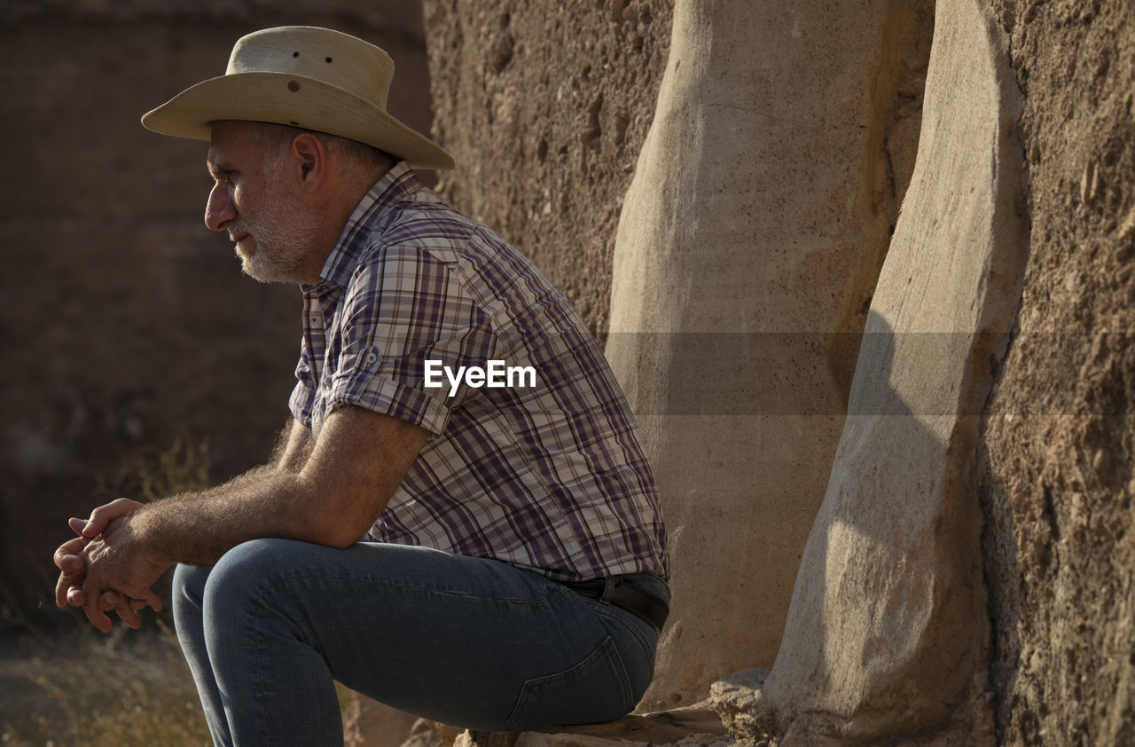 Adult man in cowboy hat and shirt sitting on step