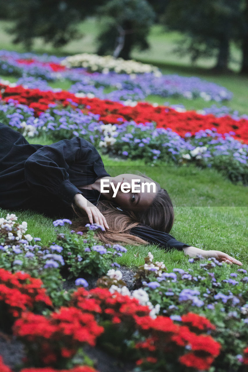 Portrait of woman lying on flowering plants