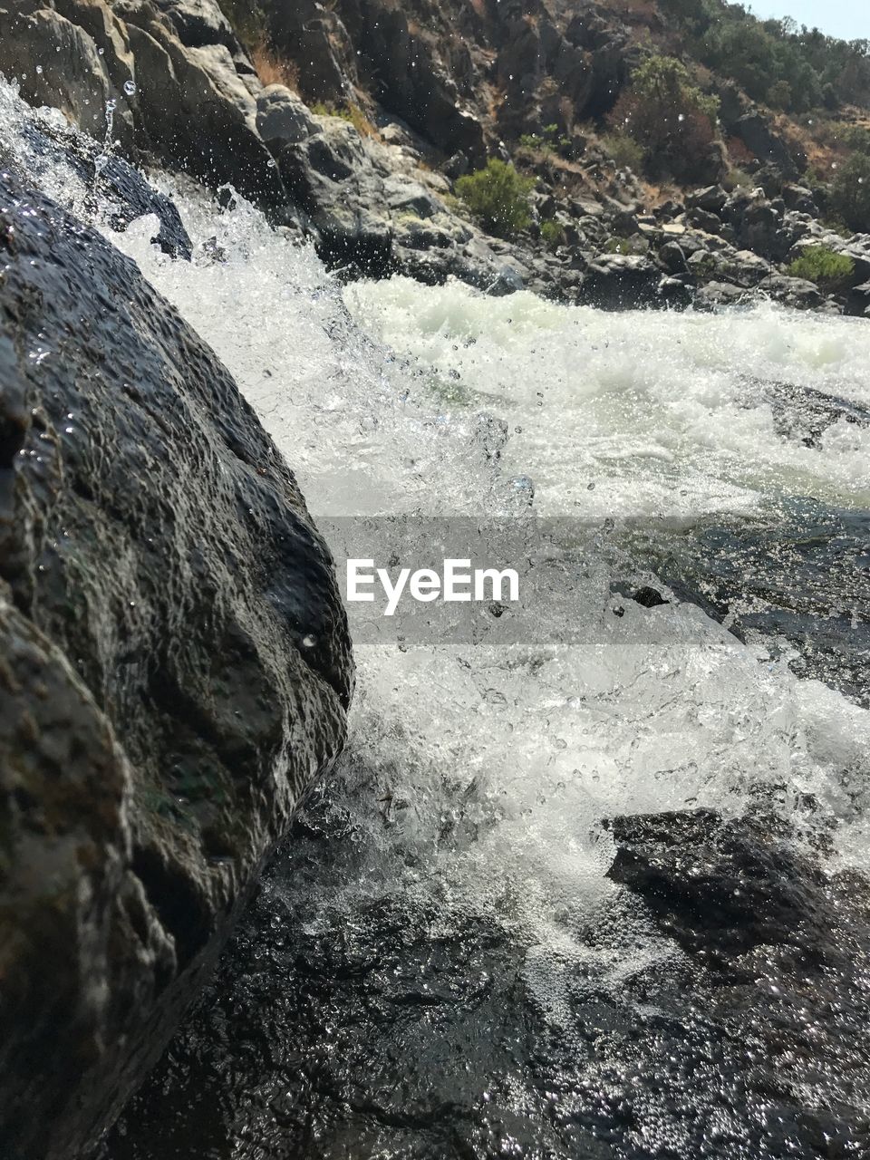 CLOSE-UP OF WATER FLOWING THROUGH ROCKS