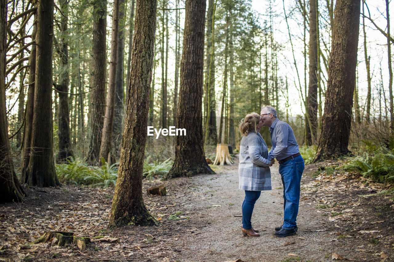 Retired couple kissing in the woods.