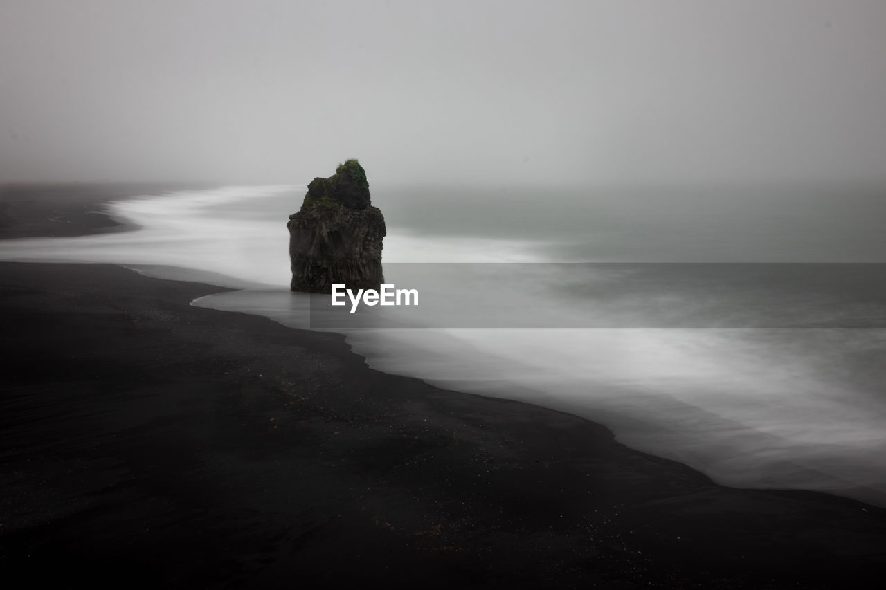 Rock formation on beach against sky