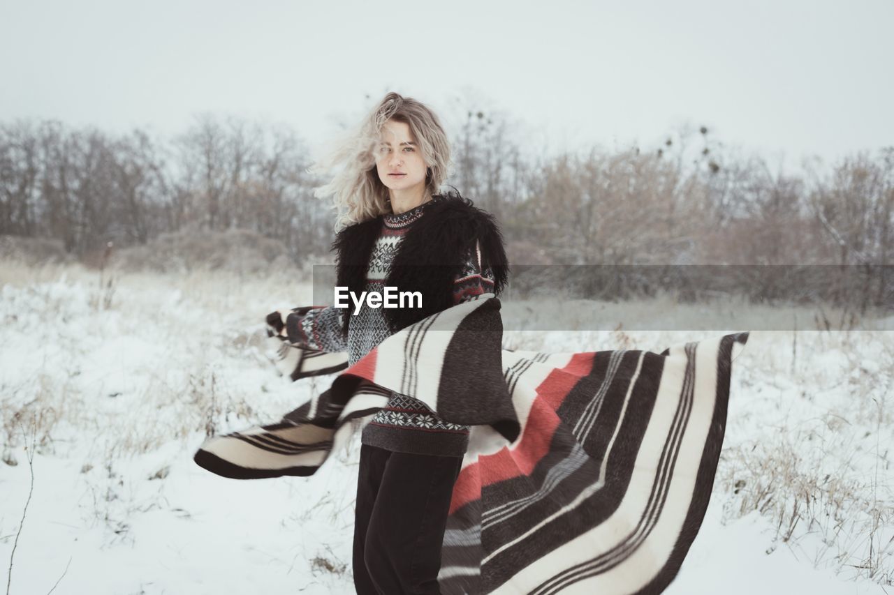 Young woman with woolen plaid in winter field scenic photography