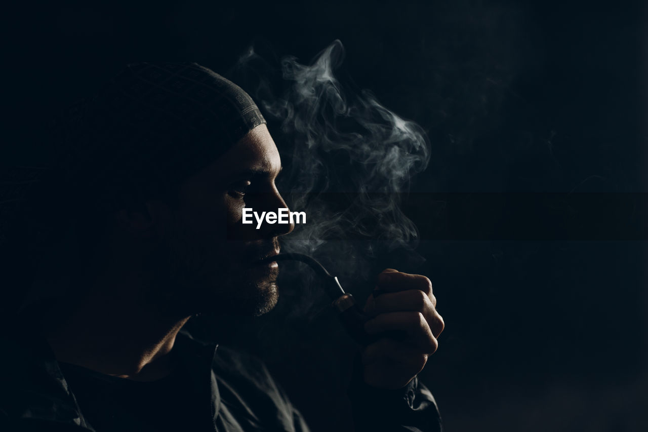 Man smoking cigarette against black background