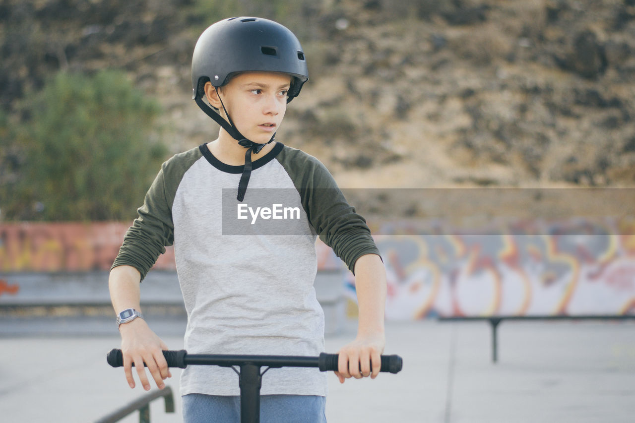 Portrait of trendy young skater wearing helmet looking away. teenager enjoying sunny day in the city