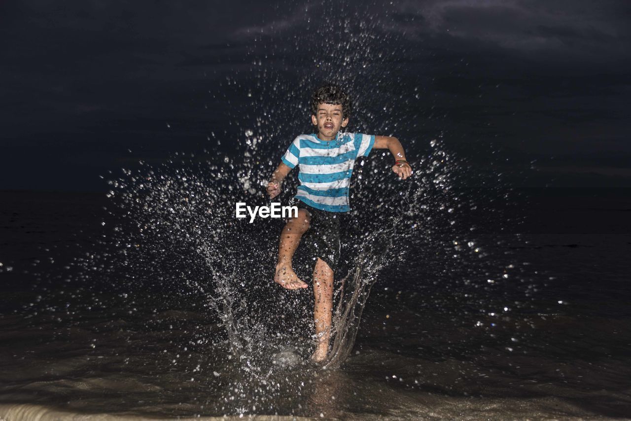 FULL LENGTH OF BOY SWIMMING IN WATER AT NIGHT