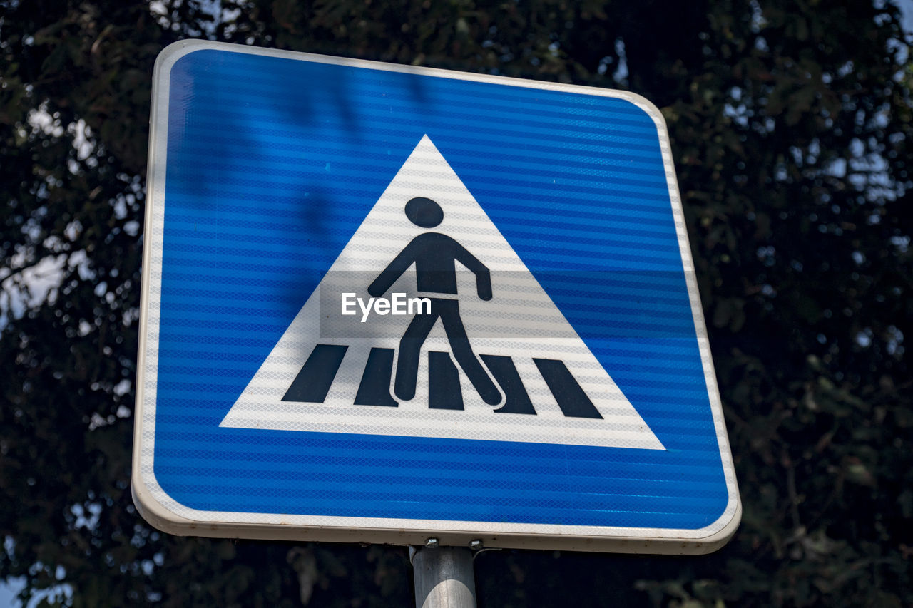 CLOSE-UP OF ROAD SIGN AGAINST BLUE WALL