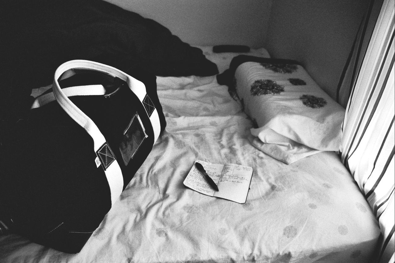 High angle view of book and luggage on bed at home