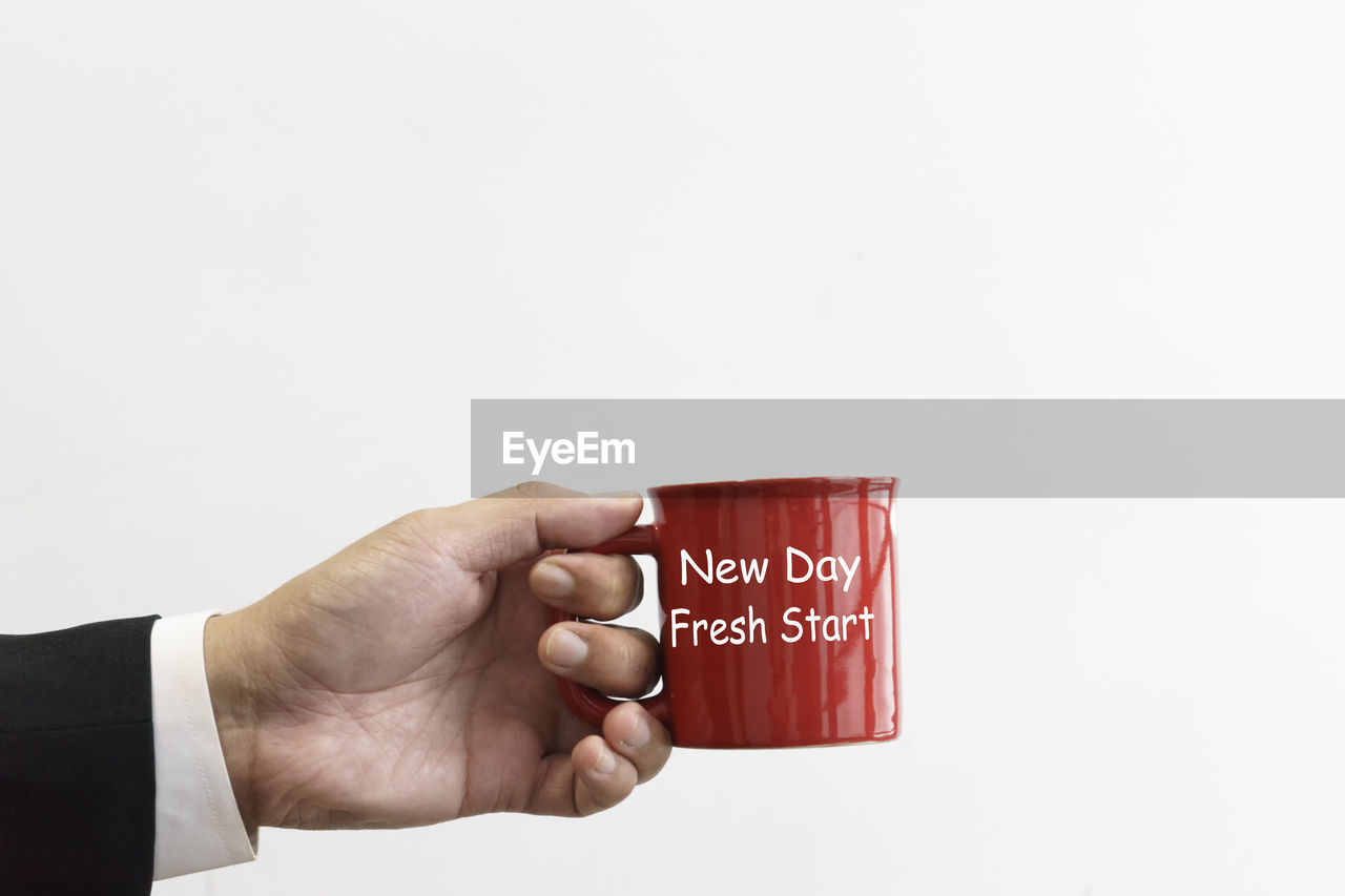 Businessman holding a red mug with text new day fresh start.