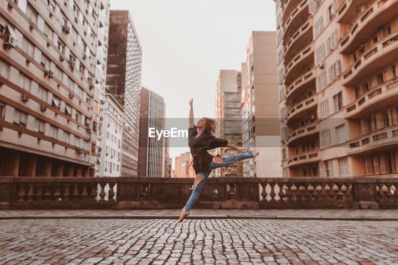 Beautiful female fashion dancer in urban sunny setting