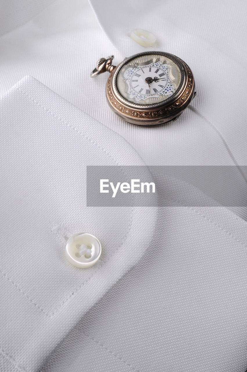 High angle view of pocket watch on shirt