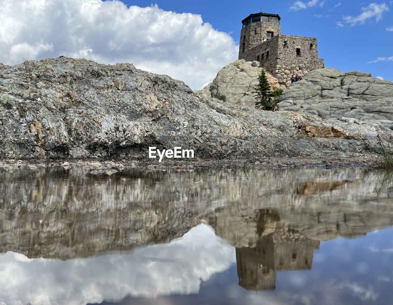 reflection, water, sky, architecture, cloud, history, nature, the past, built structure, lake, travel destinations, mountain, building, castle, rock, building exterior, travel, no people, scenics - nature, landscape, outdoors, day, beauty in nature, tranquility, tourism, fort, ancient, winter, environment, mountain range, cliff, terrain, old, land, blue