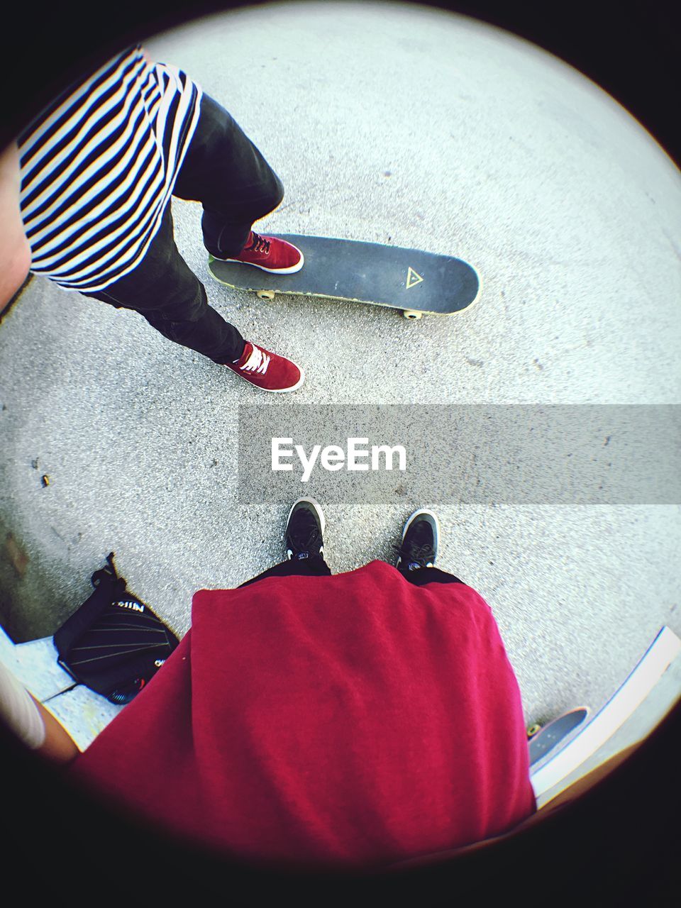 Low section of men with skateboard standing on road