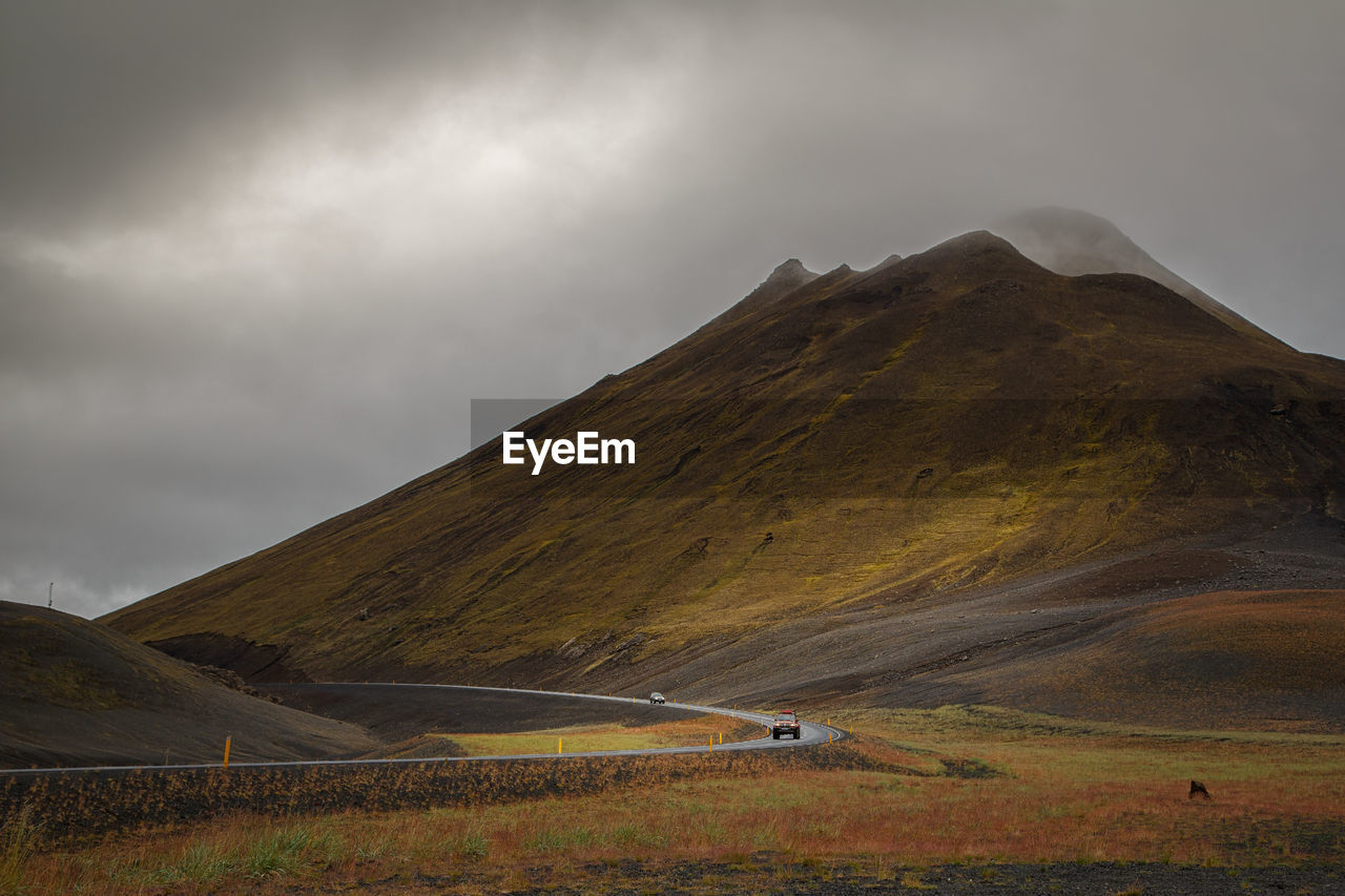 Vehicle on road by mountain against sky