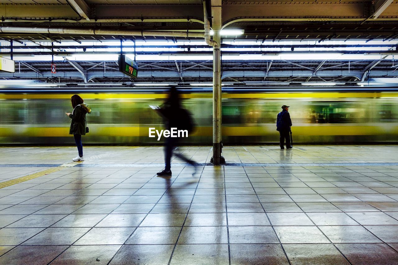 Blurred motion of train by people at railroad station platform