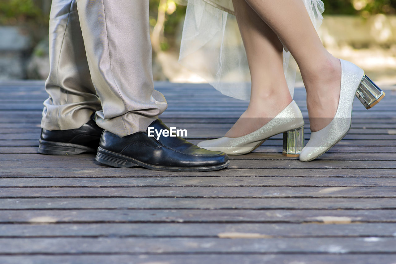 Low section of couple standing on floorboard