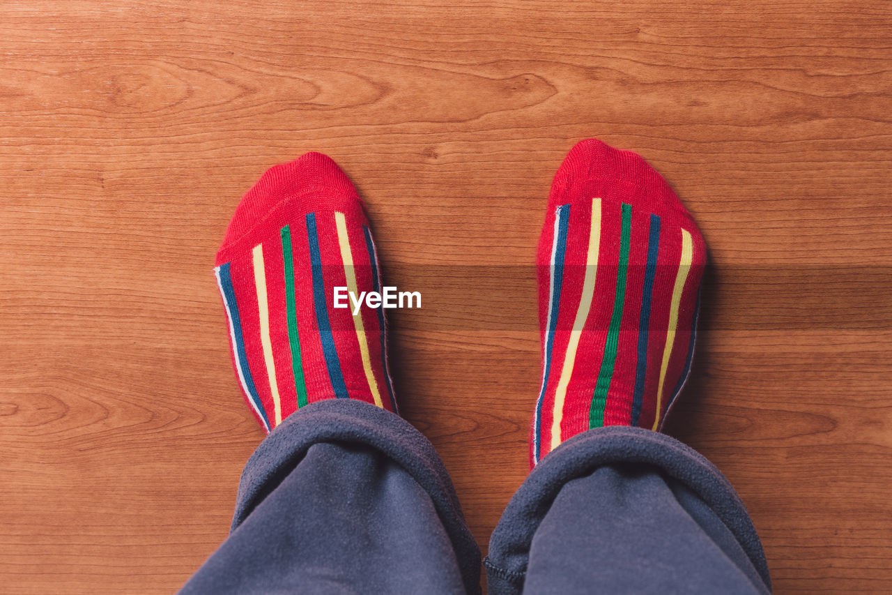 Low section of person wearing socks on wooden floor