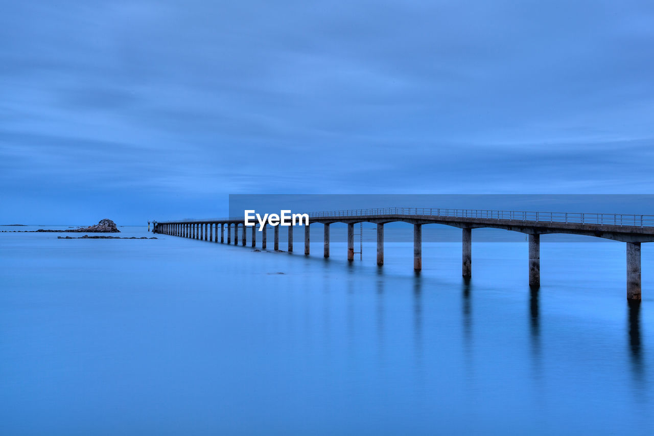 Bridge over sea against blue sky