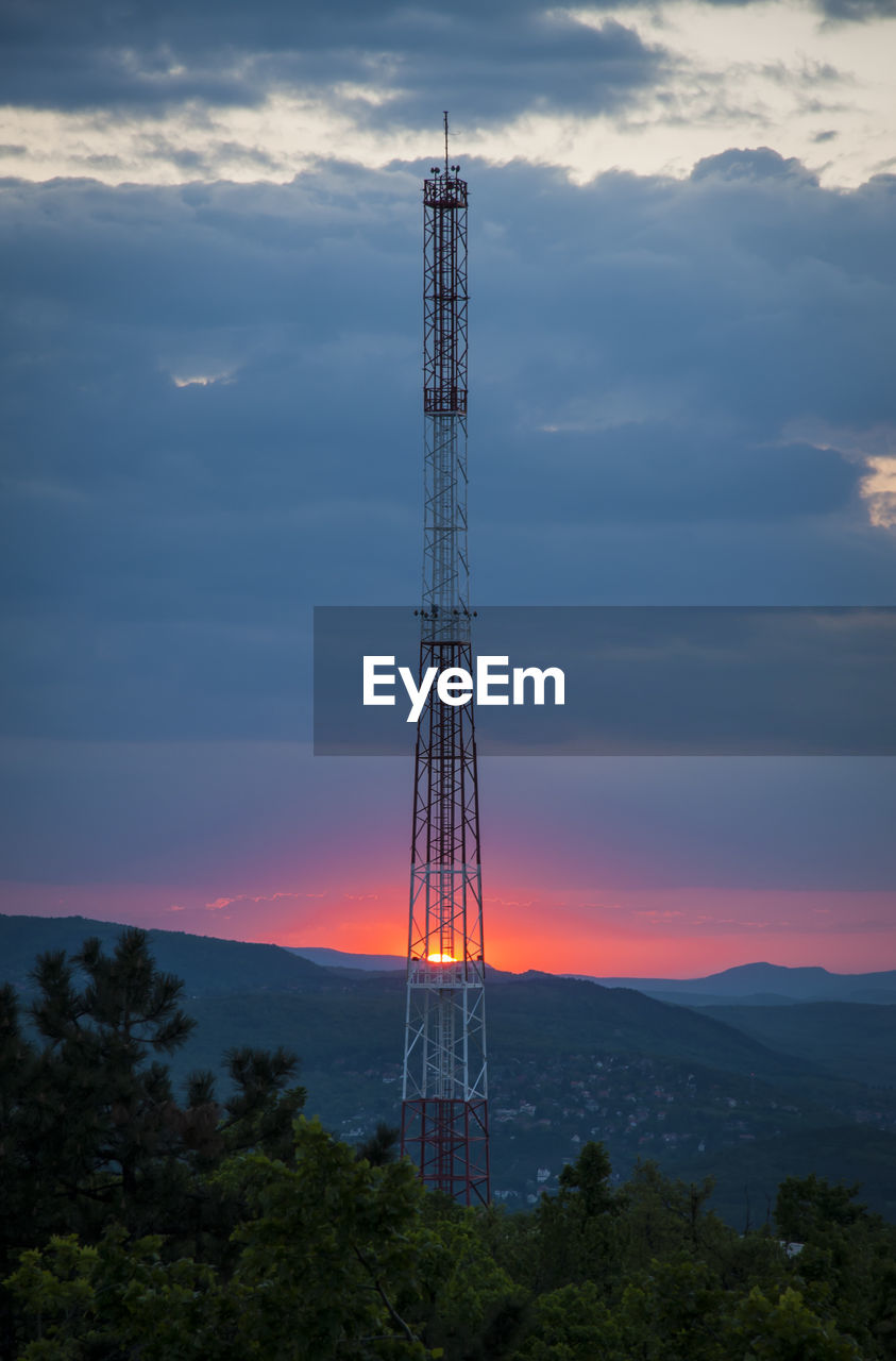 LOW ANGLE VIEW OF COMMUNICATIONS TOWER AGAINST SKY AT SUNSET