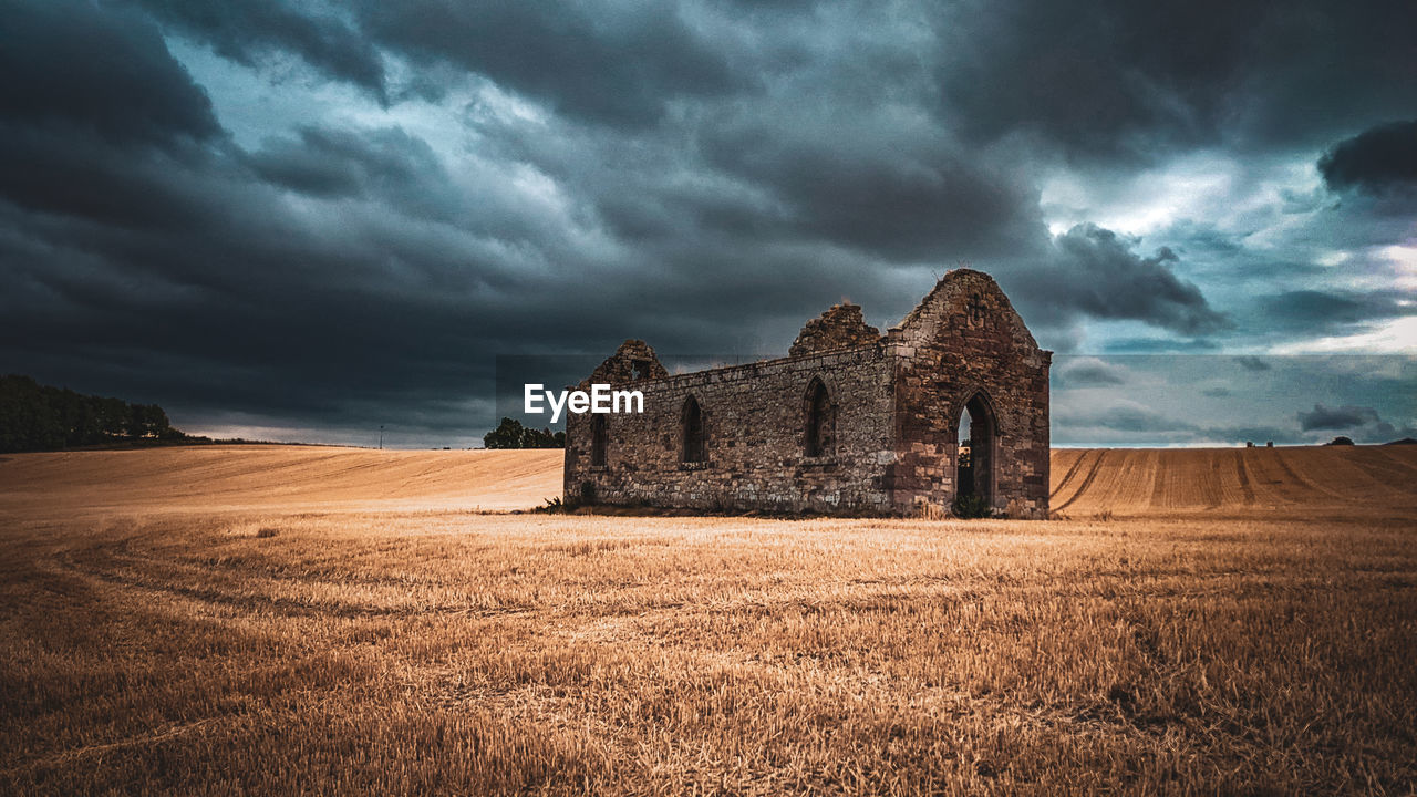 House on field against sky ruins chapel