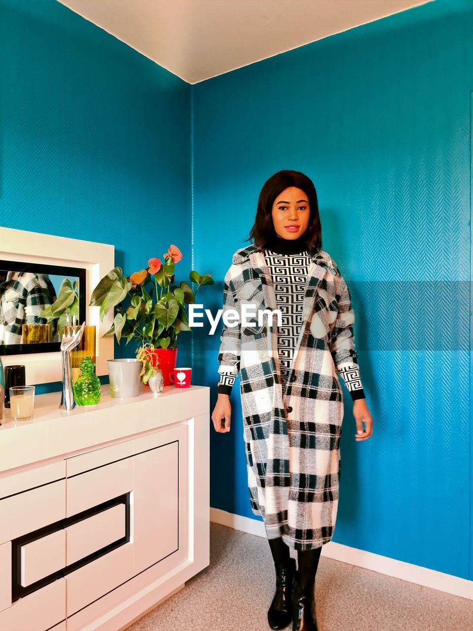 PORTRAIT OF WOMAN STANDING AGAINST BLUE WALL