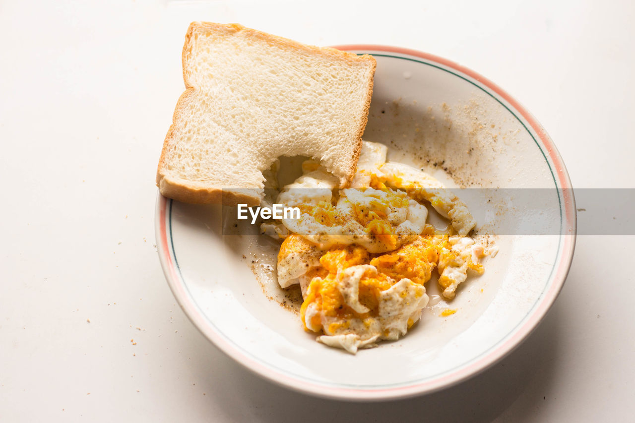 Breakfast scrambled eggs and bite bread in white dish in morning