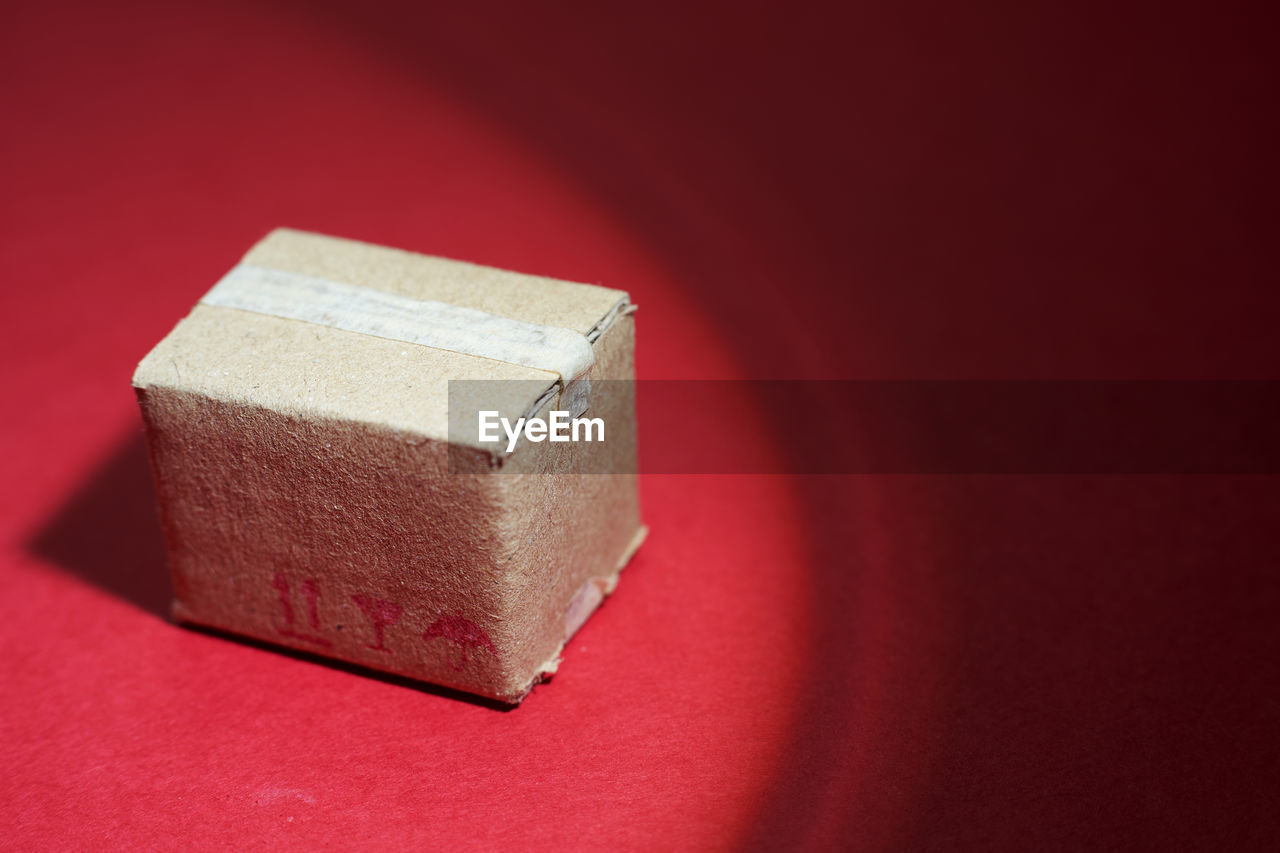 Miniature cardboard box on red background