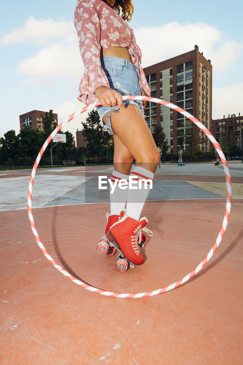 Woman wearing roller skates holding hoop at sports court