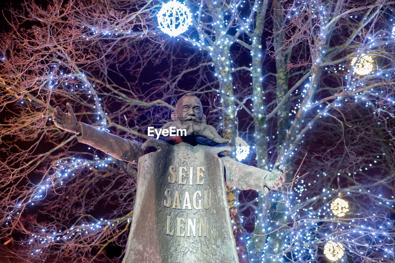 LOW ANGLE VIEW OF ILLUMINATED STATUE AGAINST SKY AT NIGHT